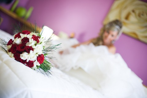 Ramo de flores en la cama con la novia de fondo.